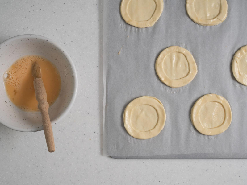 Na blasze do pieczenia ciasto francuskie posmarowane jajkiem.