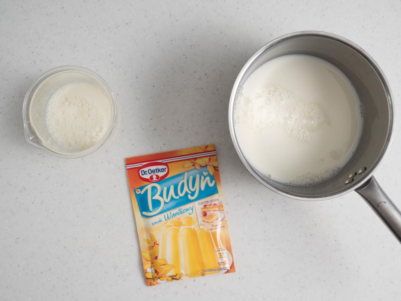 Mleko w garnku. Obok budy艅 i miarka z cukrem.