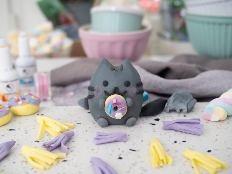 Pusheen z masy cukrowej trzymający donuta.