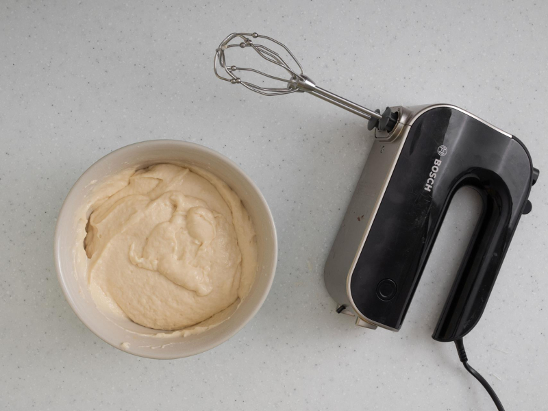 Na blacie kuchennym mikser ręczny oraz zmiksowane ciasto w misce.