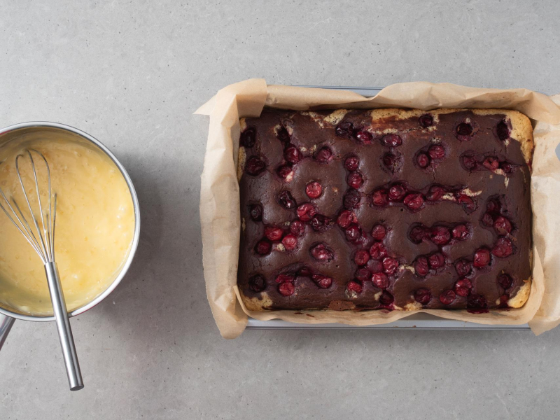 Krem budyniowy w garnku. Obok upieczone ciasto.