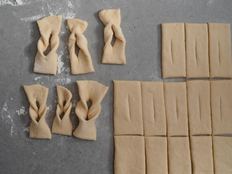 Rozwałkowane ciasto potnij na prostokąty, następnie każdy z nich natnij pośrodku, przewijając jeden koniec przez otwór.