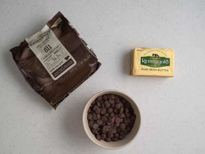 Na blacie kuchennym kostka masła oraz czekolada w miseczce.