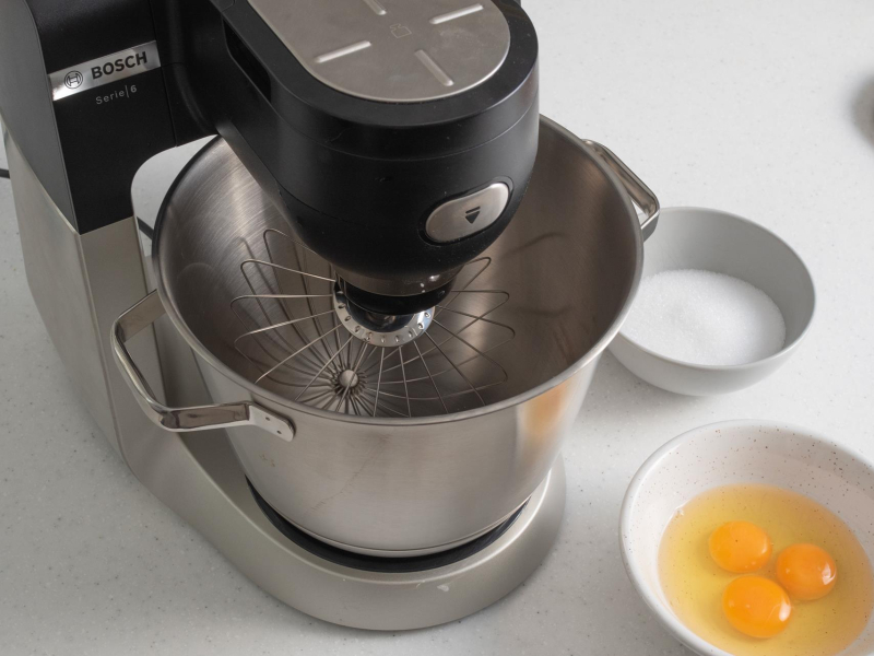 Robot kuchenny na blacie, a obok miseczka z jajkami oraz z erytrytolem.