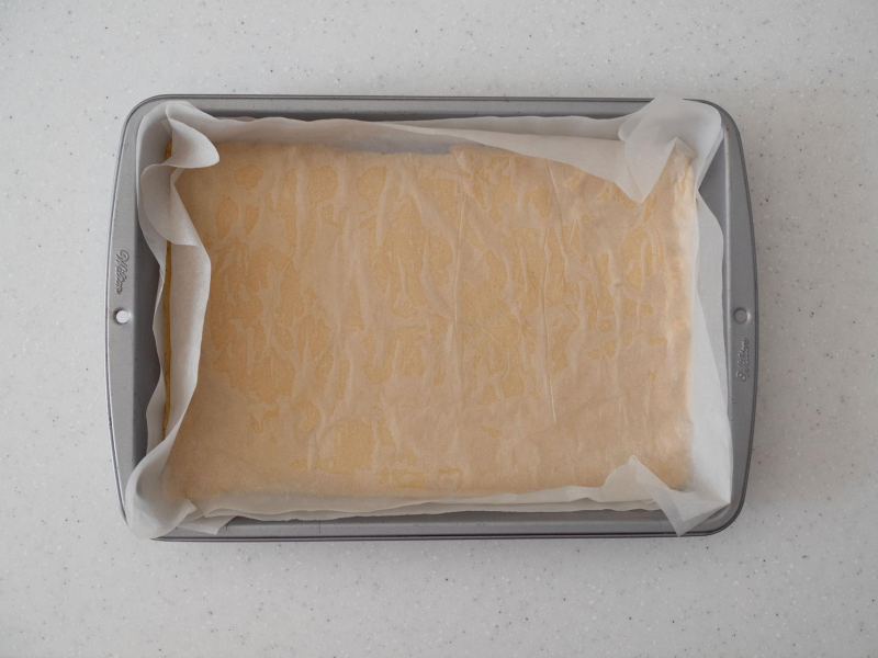 w formie do pieczenia wyłożone ciasto rozwałkowane pomiędzy papierem do pieczenia