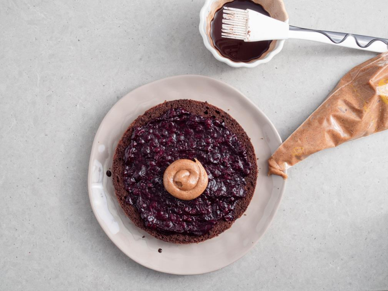 na talerzu biszkopt kakaowy posmarowany dżemem z czarnej porzeczki