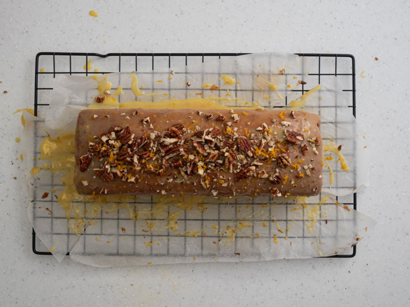 Gotowa babka pomarańczowa z polewą z białej czekolady i orzechami pekan.