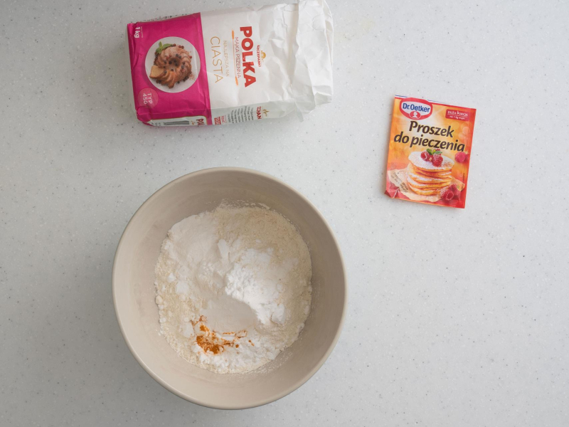 W misce mąka pszenna, ziemniaczana i kurkuma. Obok opakowanie proszku do pieczenia oraz mąki.