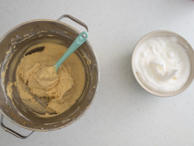 Wymieszane ciasto na babkę pomarańczową. Obok ubite białka.