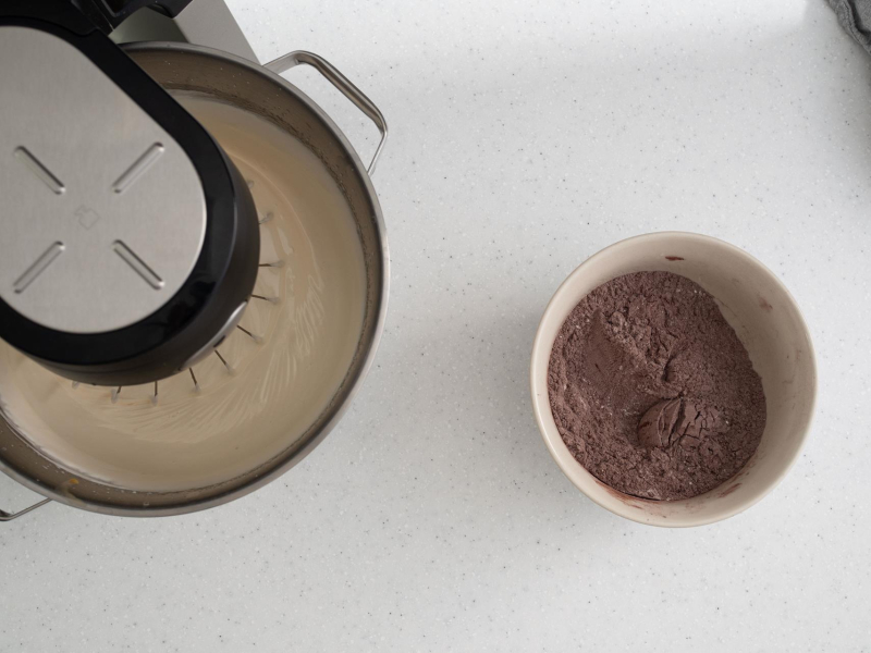 Masa biszkoptowa w mikserze. Obok w misce  wymieszane suche składniki.