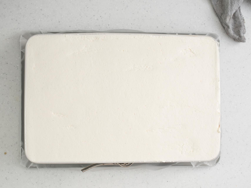 Na górze ciasta rozsmarowana śmietanka.