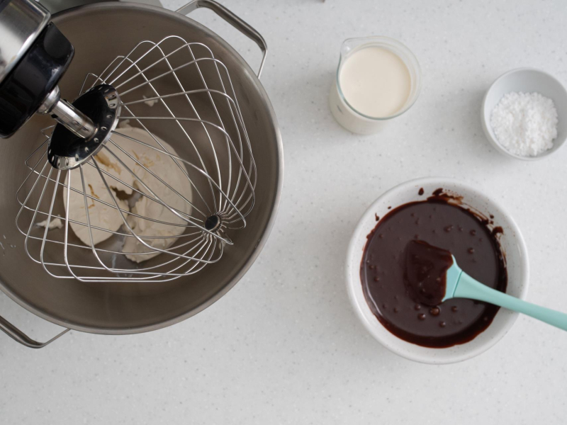 W misce mascarpone. Obok miseczka z roztopionymi cukierkami, śmietanką i cukrem pudrem.