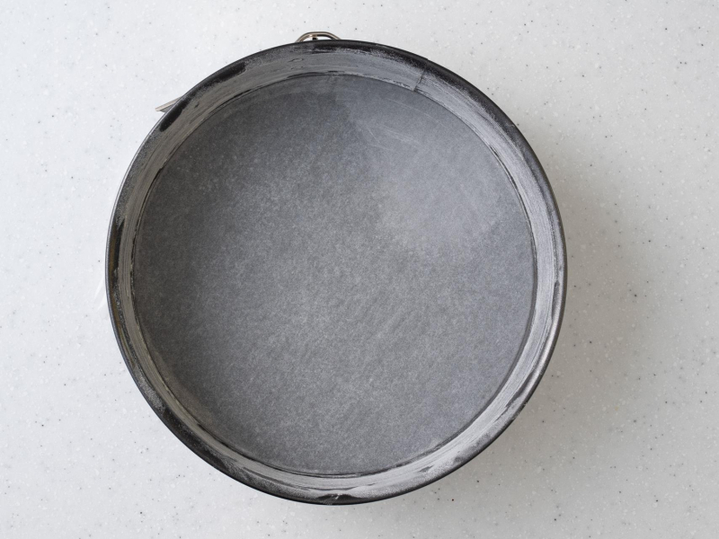 Okrągła tortownica wyłożona papierem do pieczenia.