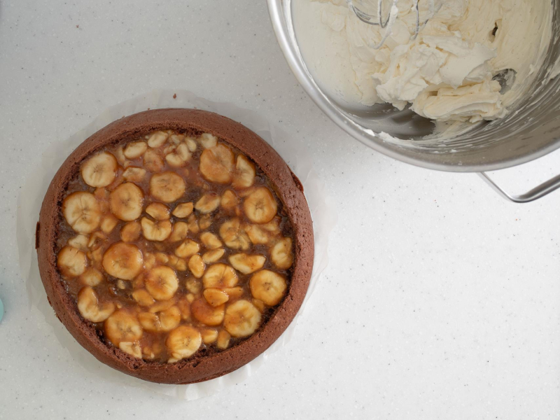 Ciasto z wyłożoną masą bananową-karmelową. Obok ubita śmietanka.