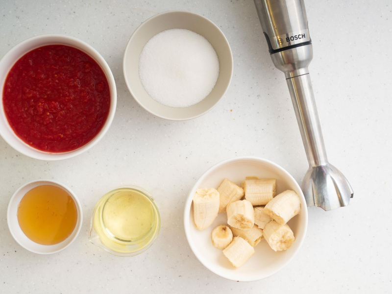 W miseczkach banany, cukier, olej, miód oraz pulpa pomidorowa.