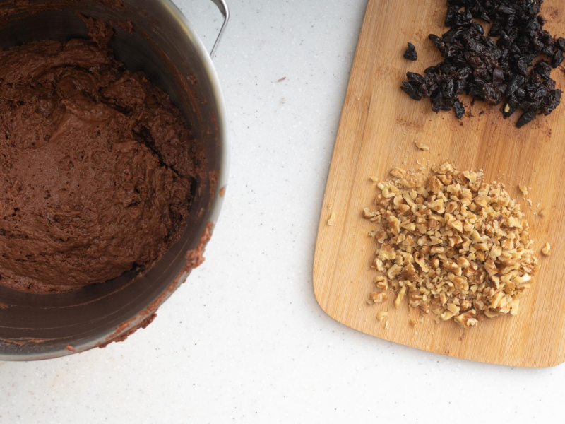 W misie wymieszane ciasto na piernik. Obok posiekane orzechy włoskie oraz pokrojone, suszone śliwki.