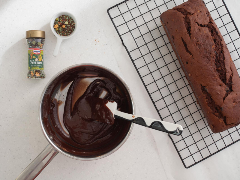 Na kratce do pieczenia piernik. Obok polewa czekoladowa i posypka cukrowa.