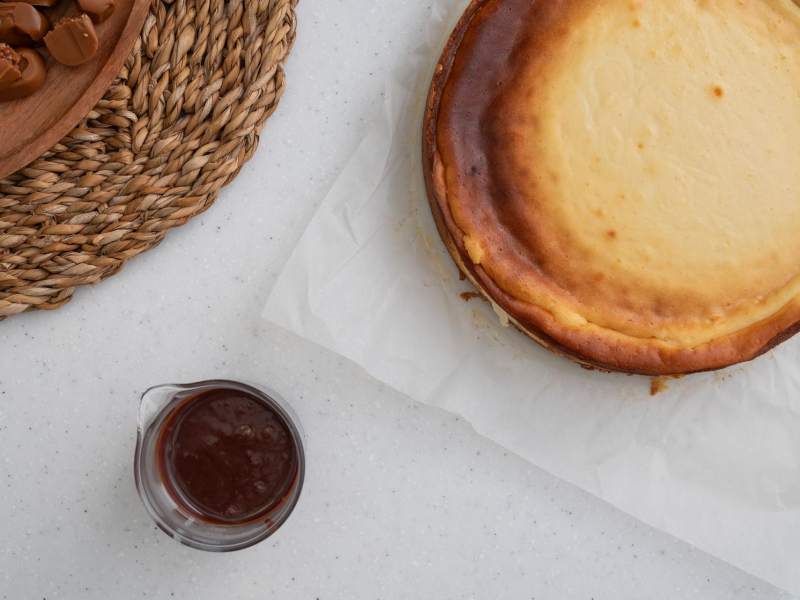 polewa z krówek do sernika w szklanym naczyniu obok sernik