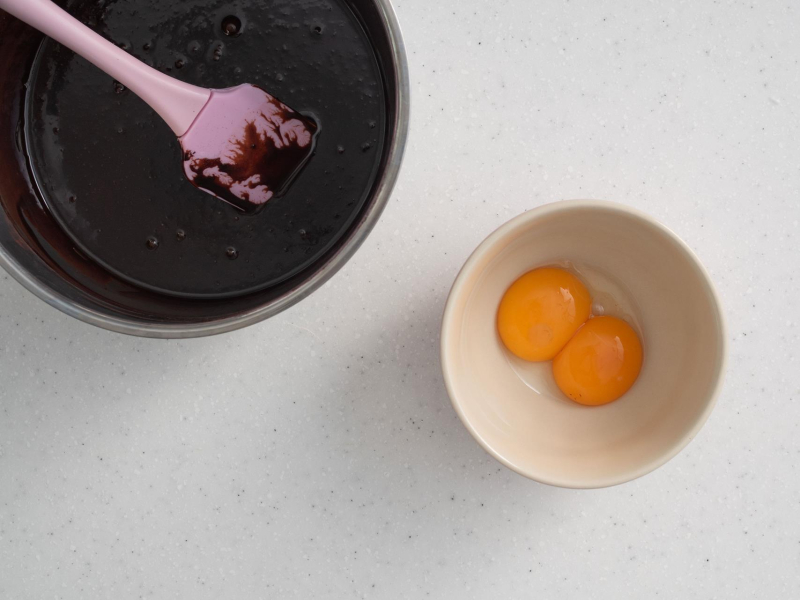 W miseczce żółtka. Obok masa czekoladowa.