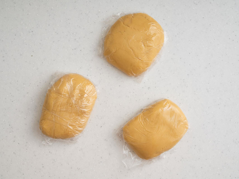 zagniecione ciasto miodowe podzielone na 3 części, owinięte folią spożywczą