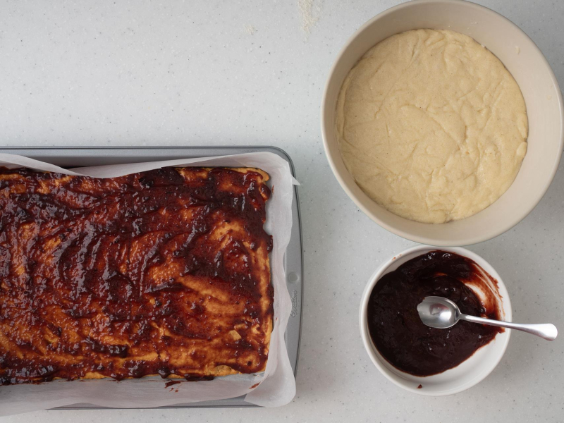 posmarowany blat miodowy powidłami śliwkowymi, obok miska z masą z kaszy manny