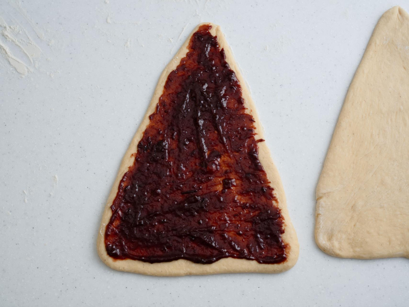 trójkąt ciasta drożdżowego posmarowany nadzieniem z powideł i czekolady