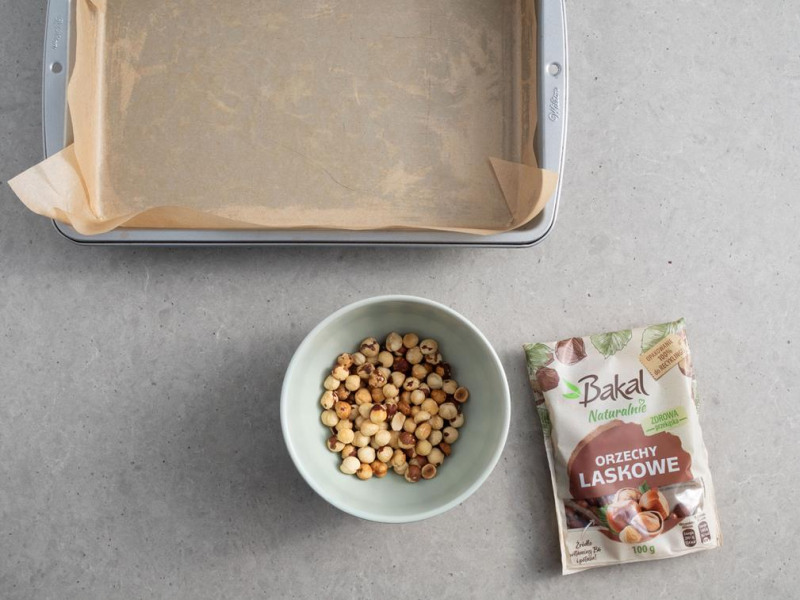 w miseczce uprażone orzechy laskowe bez skórki i forma do pieczenia