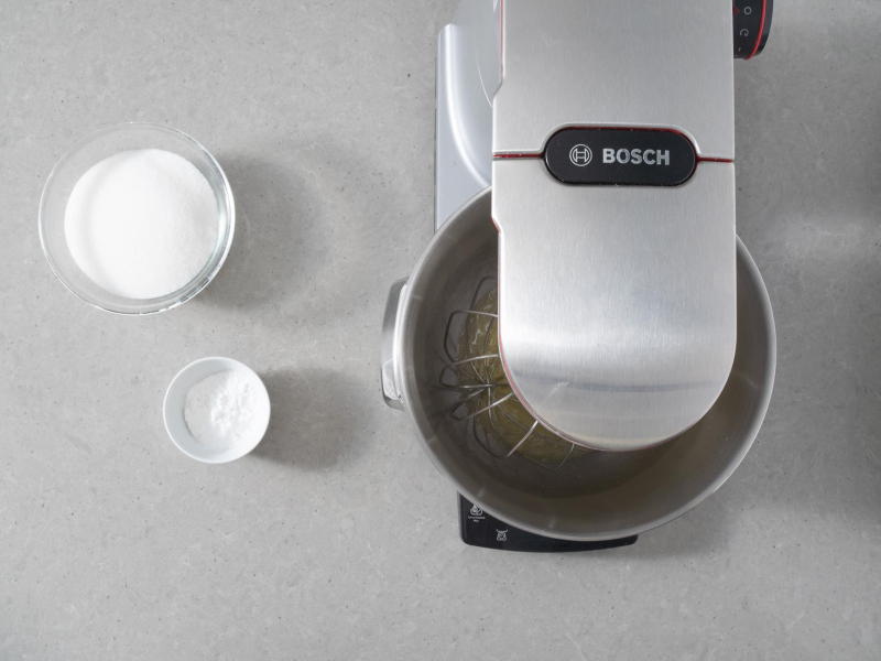 Białka w misie robota kuchennego. Obok w miseczce cukier oraz skrobia ziemniaczana.