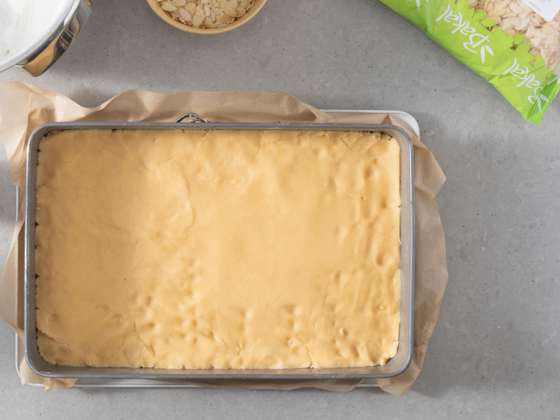 Rozwałkowany blat ciasta kruchego w prostokątnej formie.