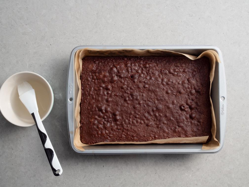 upieczony spód Bounty, obok miseczka z ponczem i pędzelkiem do nasączania