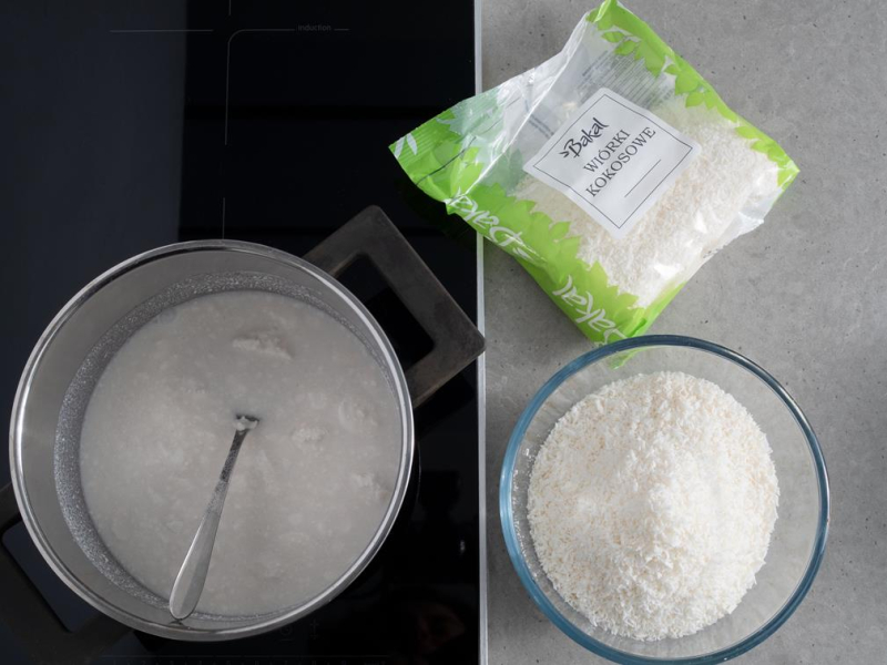 w garnku mleko kokosowe obok wiórki kokosowe Bakal