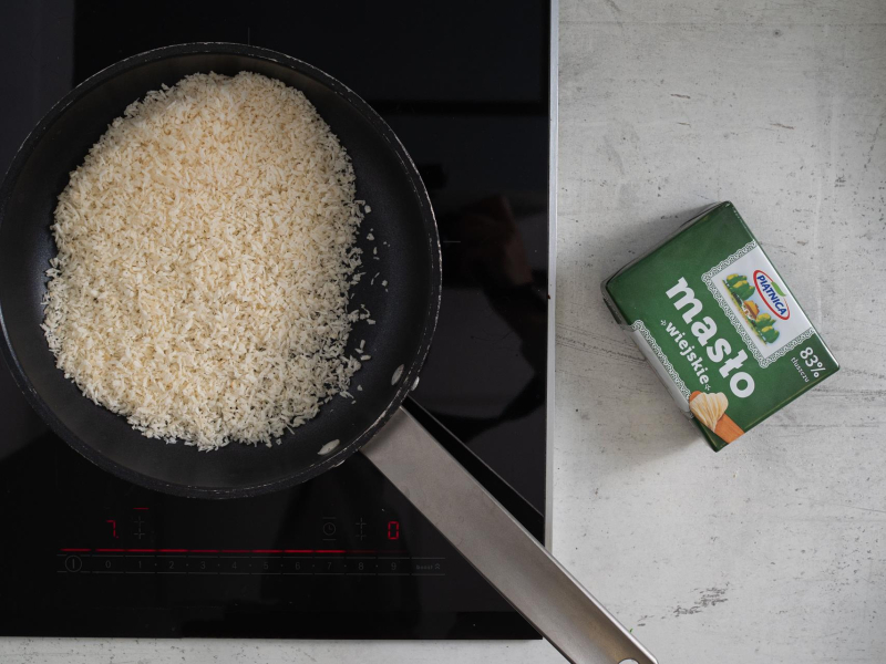 Na patelni wiórki kokosowe i masło na blacie.