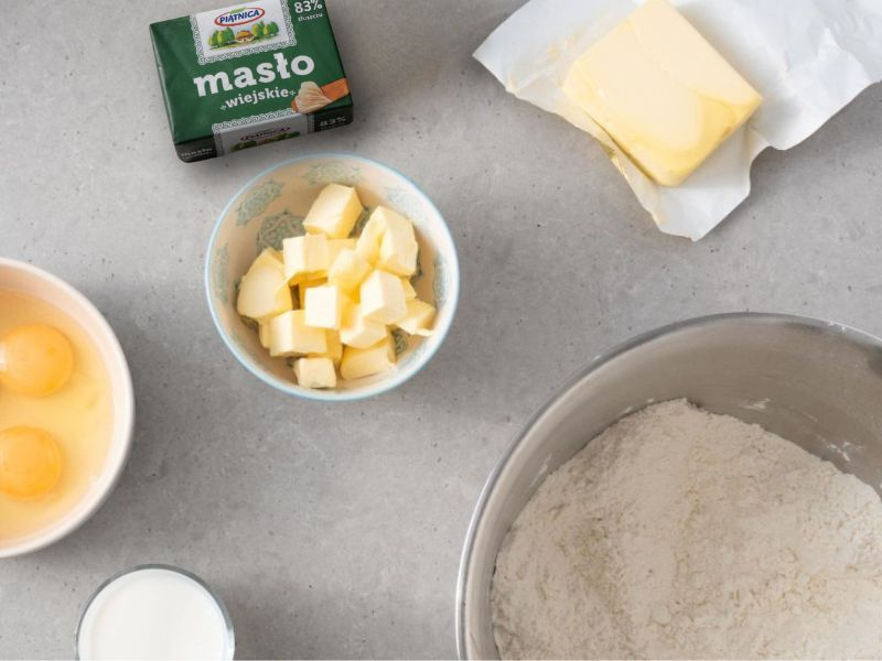 Na blacie kuchennym masło, jajka, ciepłe mleko oraz wymieszane suche składniki
