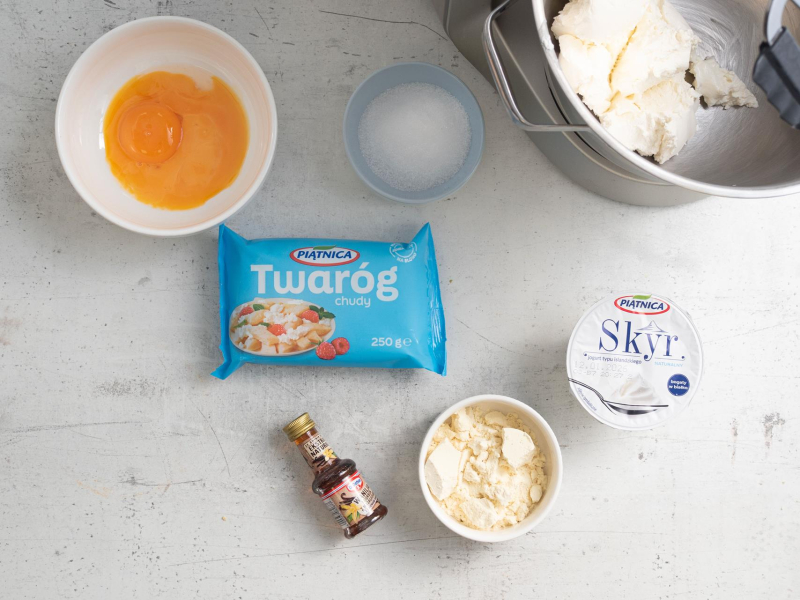 W misie twaróg zblendowany ze skyrem. Obok w miseczce odżywka białkowa, jajka, ekstrakt waniliowy oraz erytrytol.