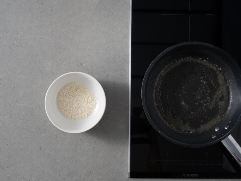 rozpuszczone masło na patelni, obok w miseczce wiórki kokosowe