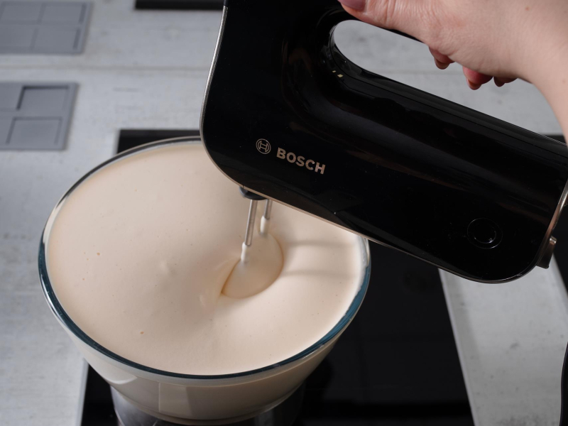 w misce nad garnkiem ubijane jajka z cukrem mikserem ręcznym bosch