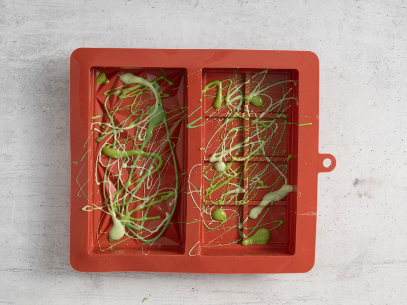 W formie silikonowej esy floresy z różnych odcieni zielonego z białej czekolady z barwnikiem.