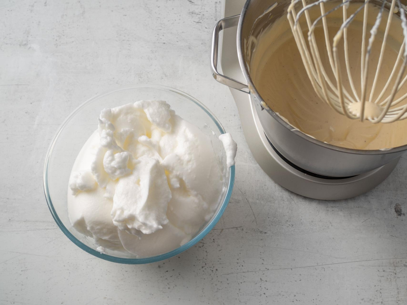 w szklanej miseczce ubite białka obok w misce robota masa serowa na sernik wiedeński