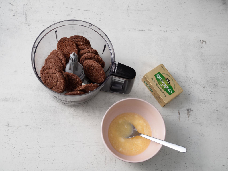 w miseczce rozpuszczone masło Kerrygold, na blacie kostka masła, w robocie ciasteczka czekoladowe