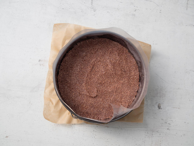okrągła tortownica z kakaowym ciasteczkowym spodem, wyłożona papierem do pieczenia