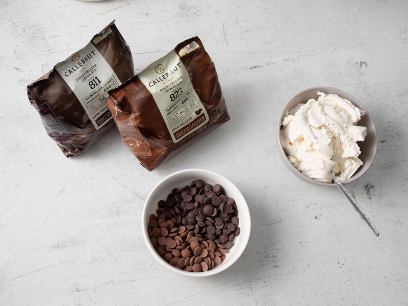 2 opakowania czekolady Callebaut 400 g, kaletki w miseczce, obok wyłożone serki Philadephia