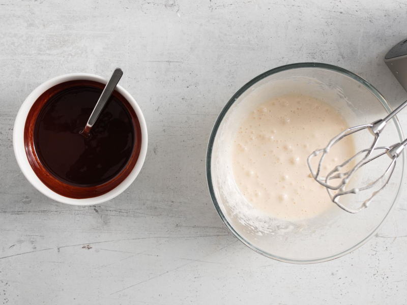 Miska z rozpuszczoną czekoladą z masłem oraz miska z ubitymi jajkami z cukrem.