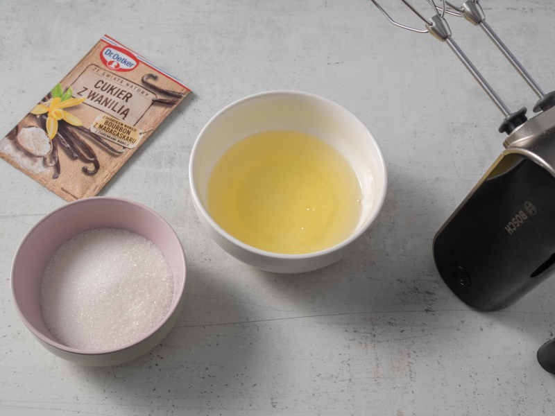 w miseczkach cukier i białka obok cukier z wanilią i mikser ręczny bosch