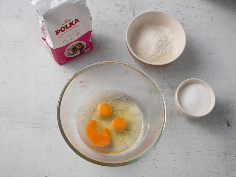 mąka polka na blacie, w misce jajka i składniki na ciasto z jabłkami