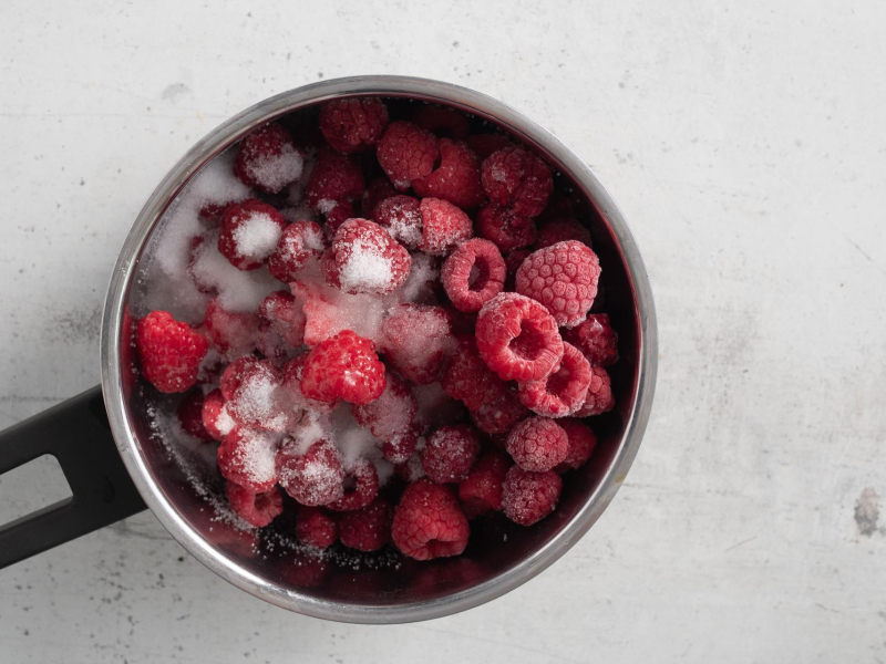 Maliny i cukier w garnku.