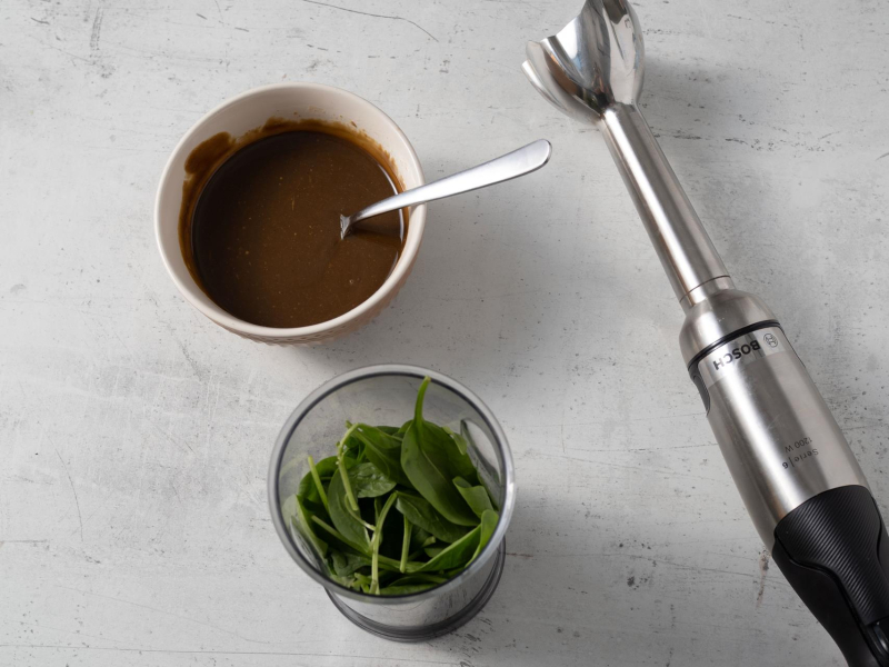 w wysokim naczyniu szpinak obok miseczka z pastą pistacjową