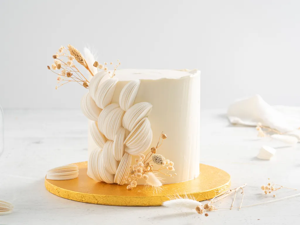 biały tort komunijny z dekoracją z papieru waflowego i suszonych kwiatów