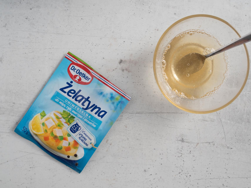 Na blacie kuchennym opakowanie żelatyny. A obok rozmieszana żelatyna w misce.