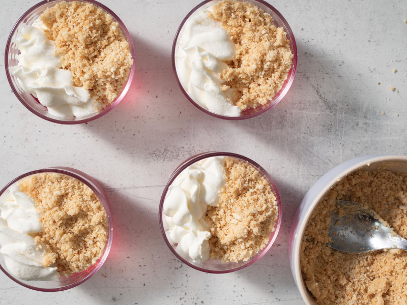 pucharki wypełnione galaretką, na wierzchy pokruszone herbatniki i bita śmietana