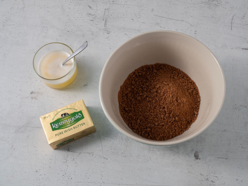 w misce pokruszone ciasteczka kakaowe obok rozpszczone masło Kerrygold